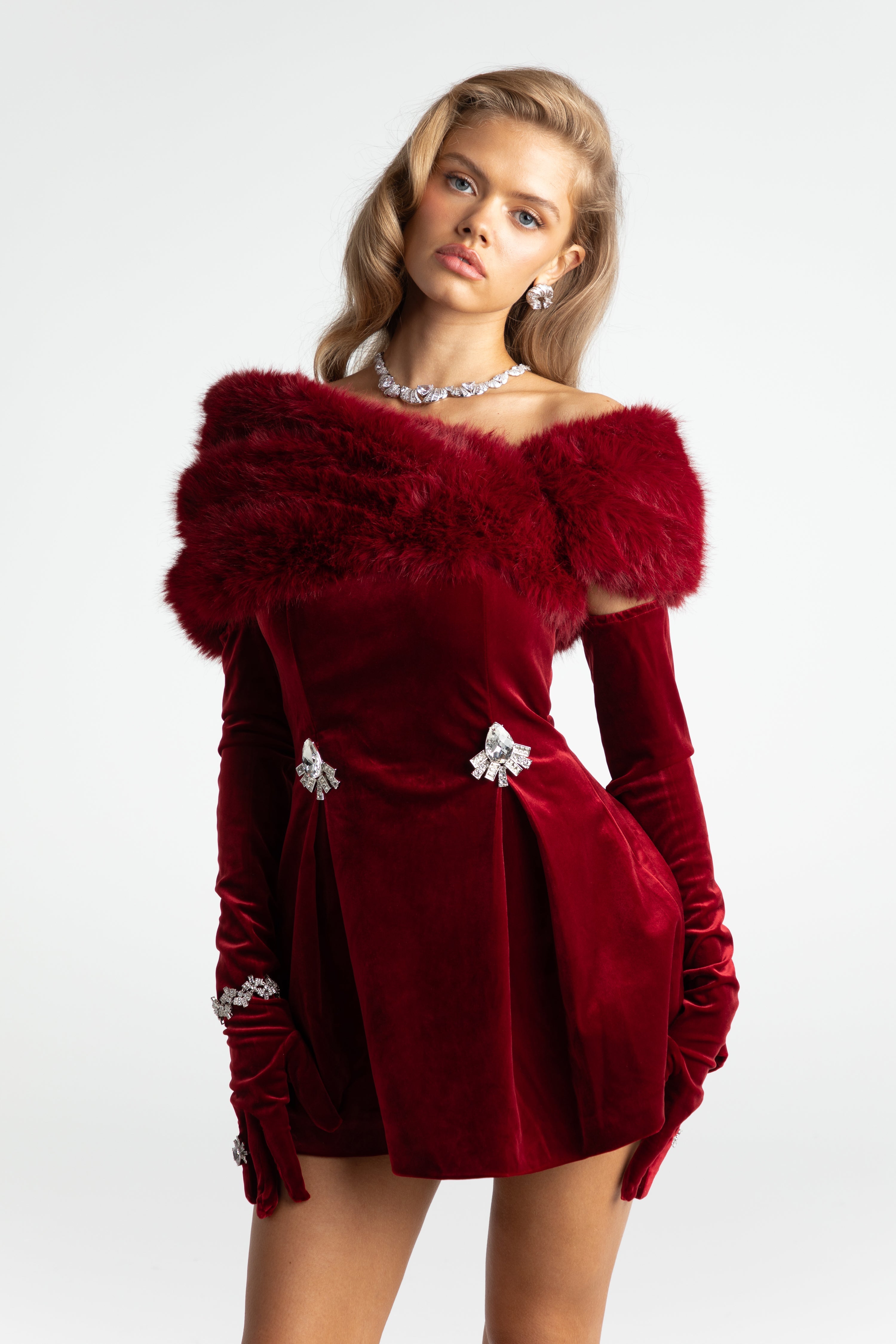 Red dress with fur trim worn by a model on a white background