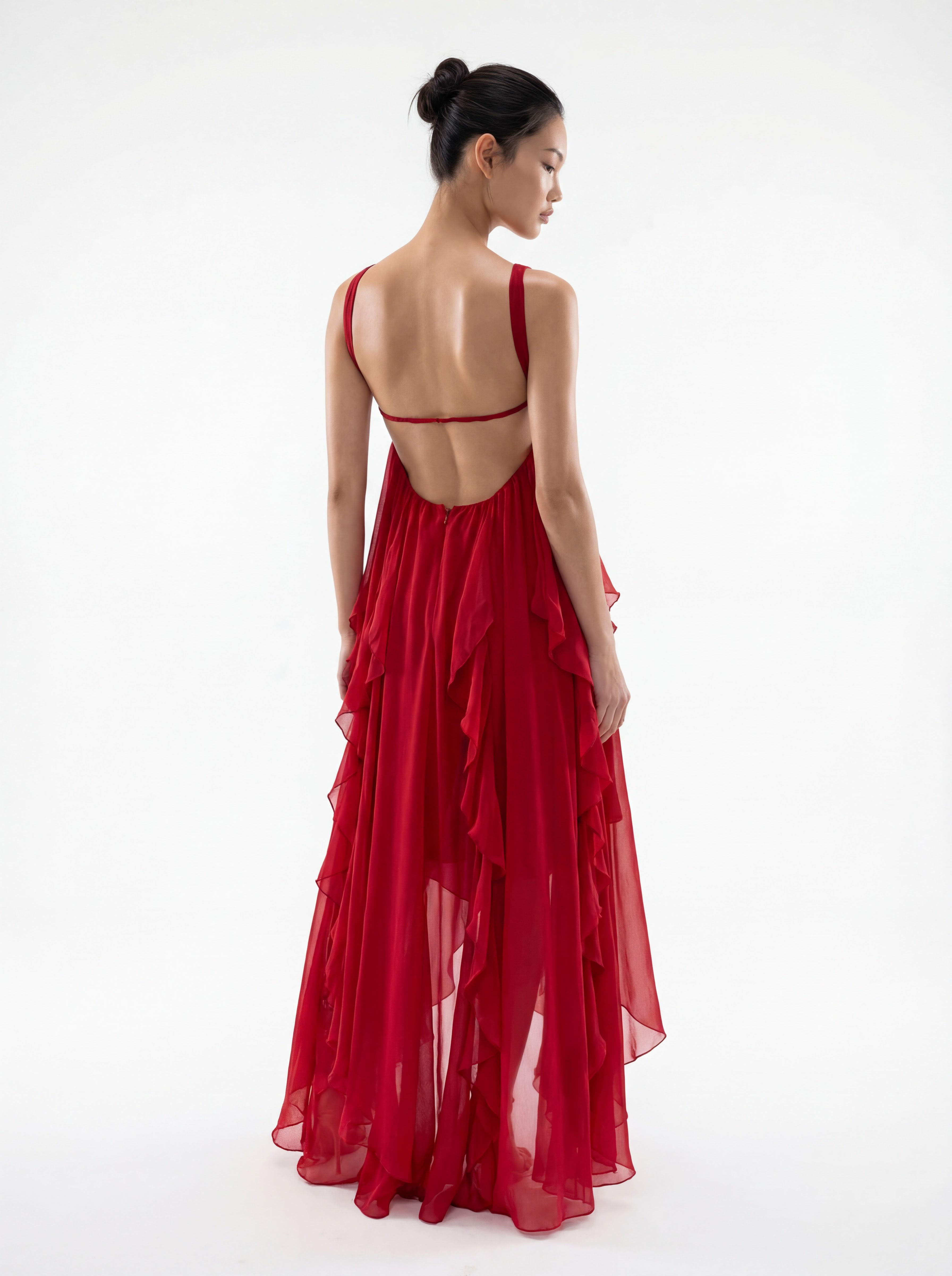 Woman wearing a red evening gown with a sheer overlay on a white background