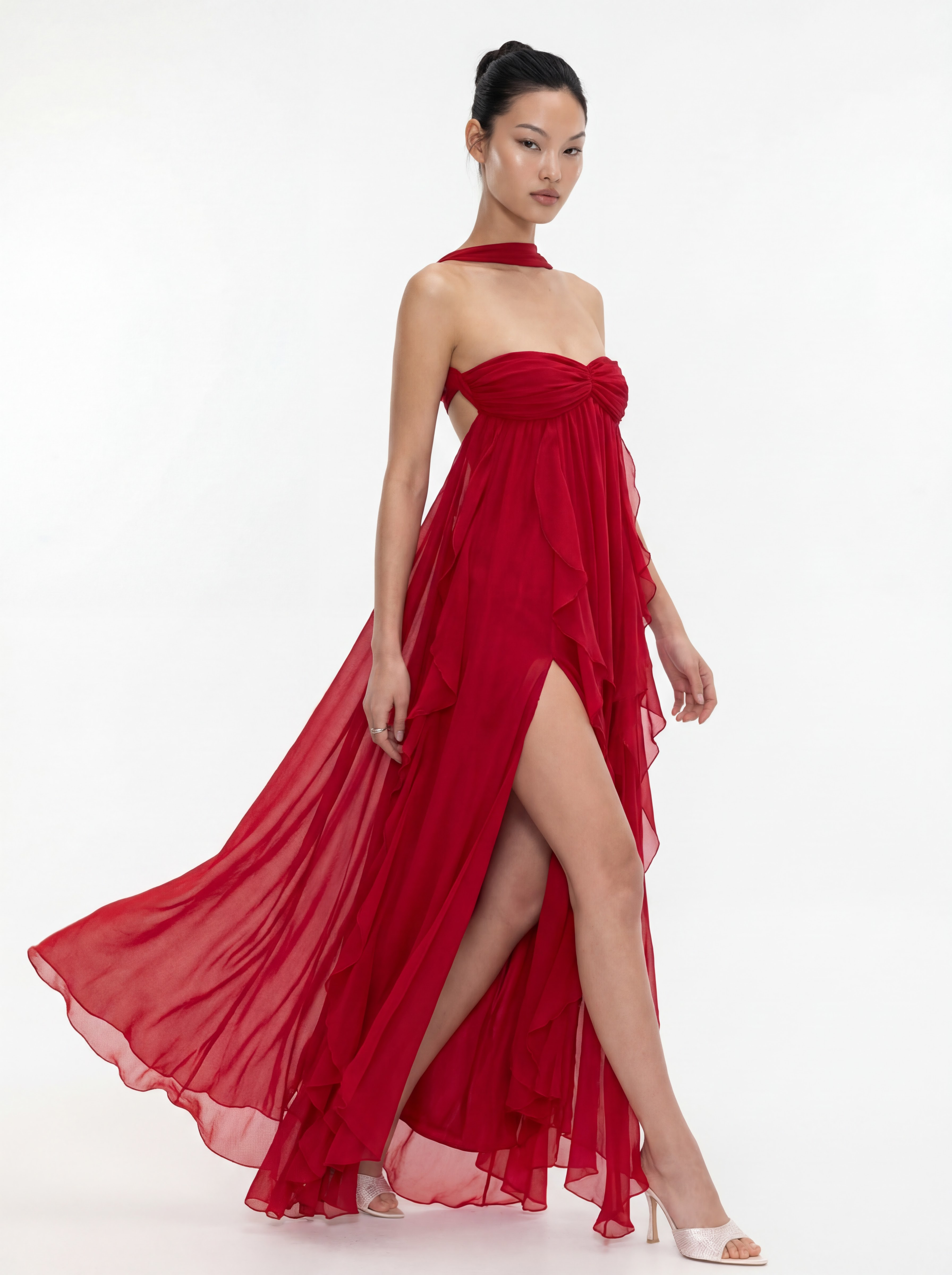 Woman wearing a red strapless gown with a slit on a white background