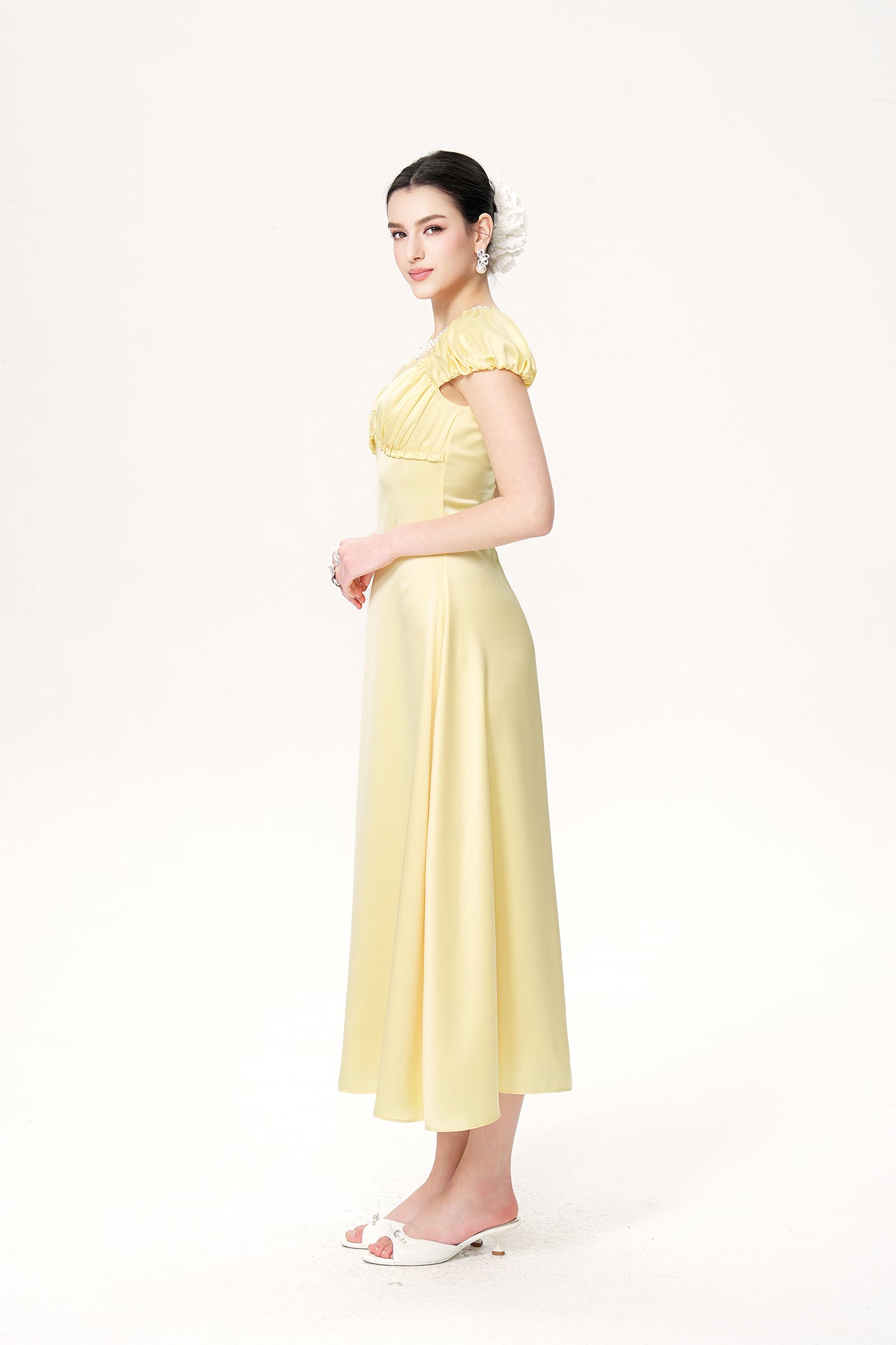 Woman wearing a light yellow dress on a white background