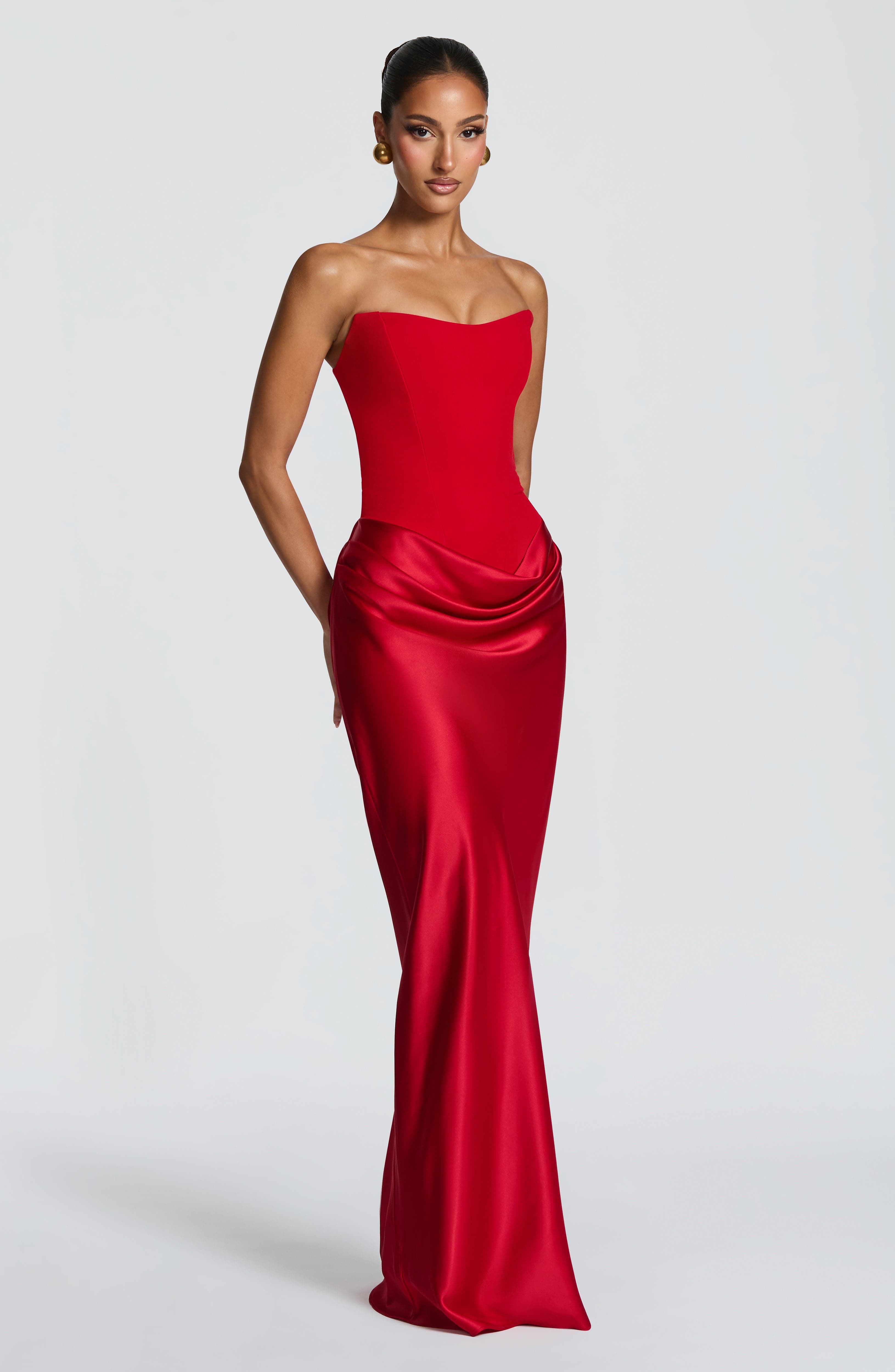 Woman wearing a strapless red evening gown on a white background