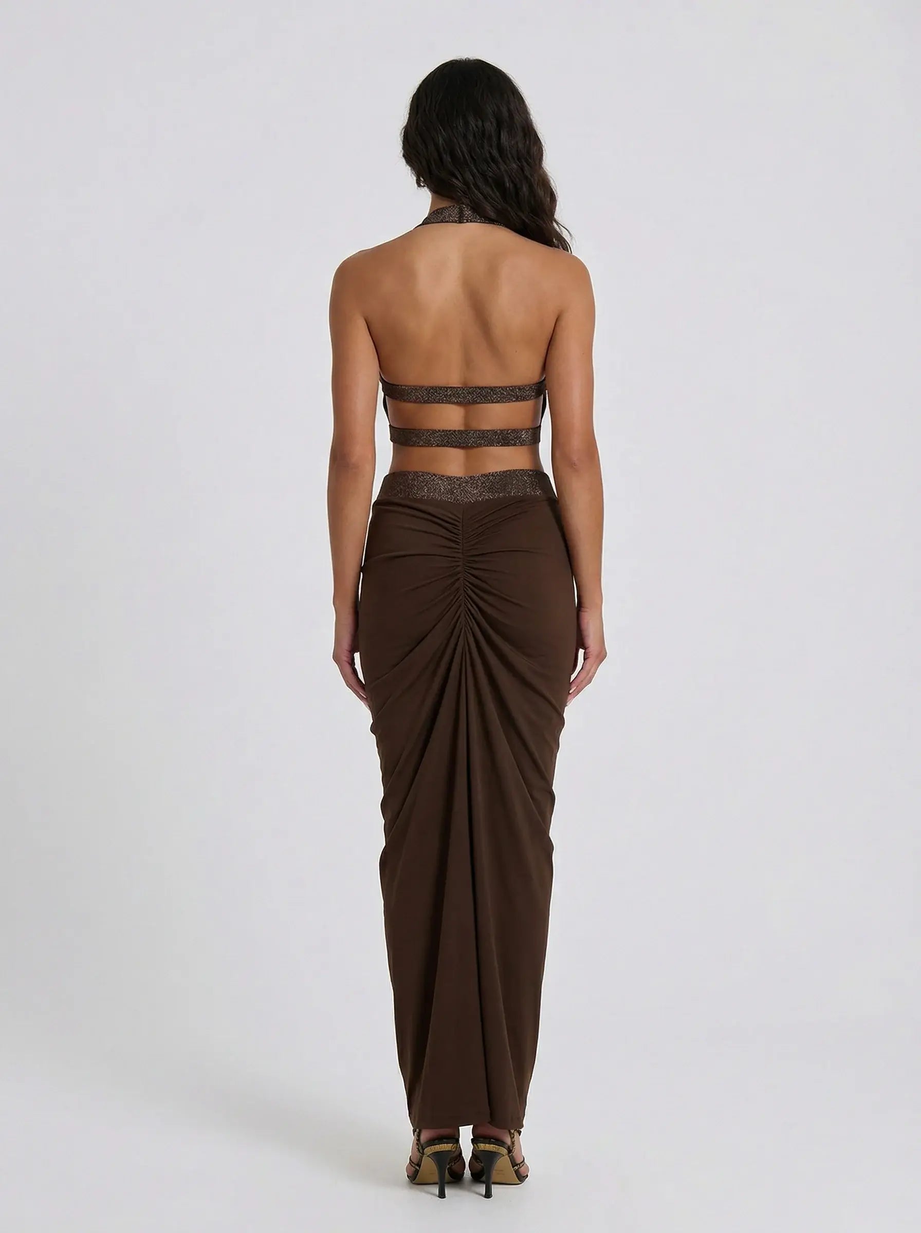 Woman wearing a brown strapless top and long skirt on a white background