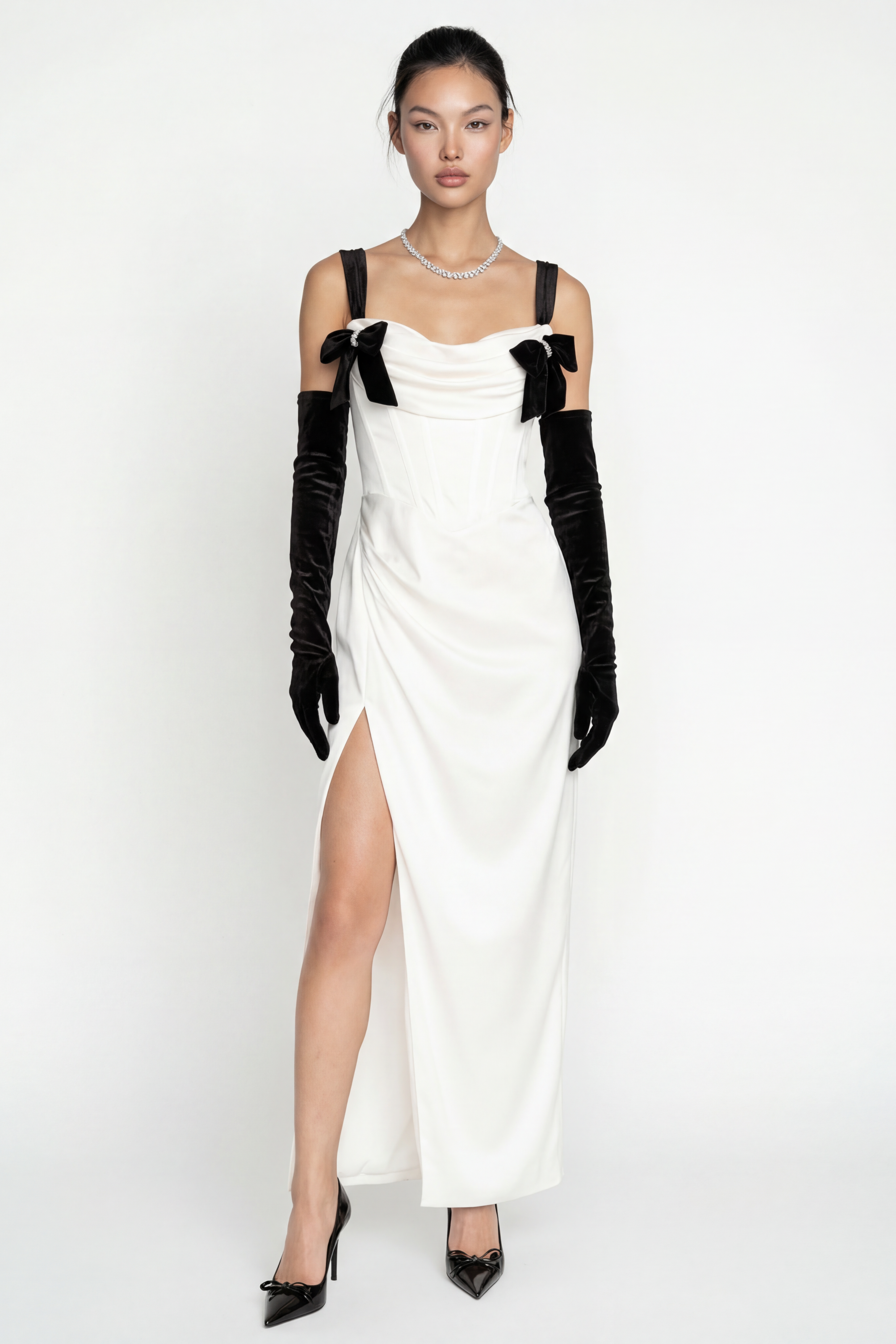 Woman wearing a white dress with black gloves and shoes on a white background