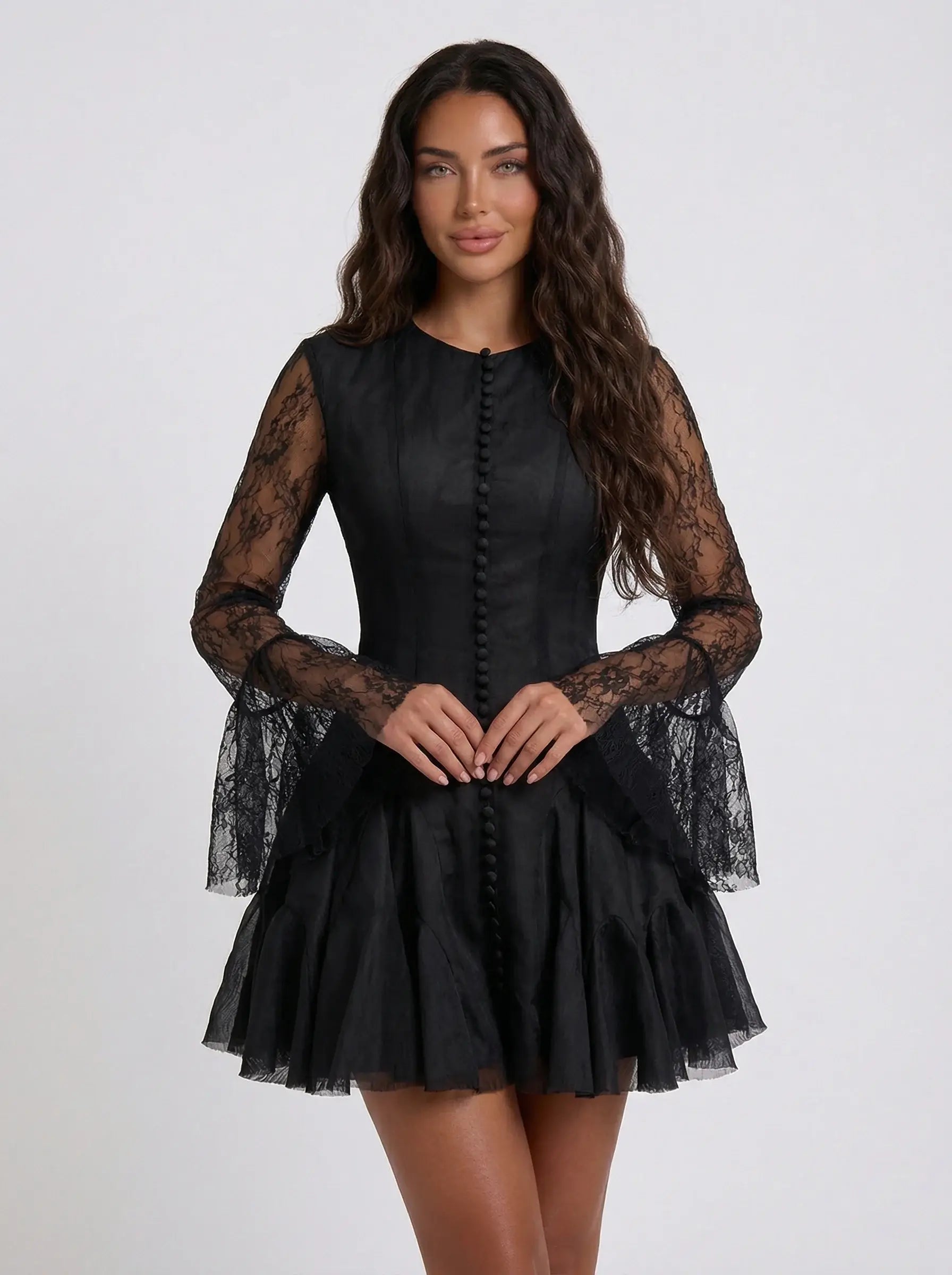 Black dress with sheer sleeves worn by a model on a white background