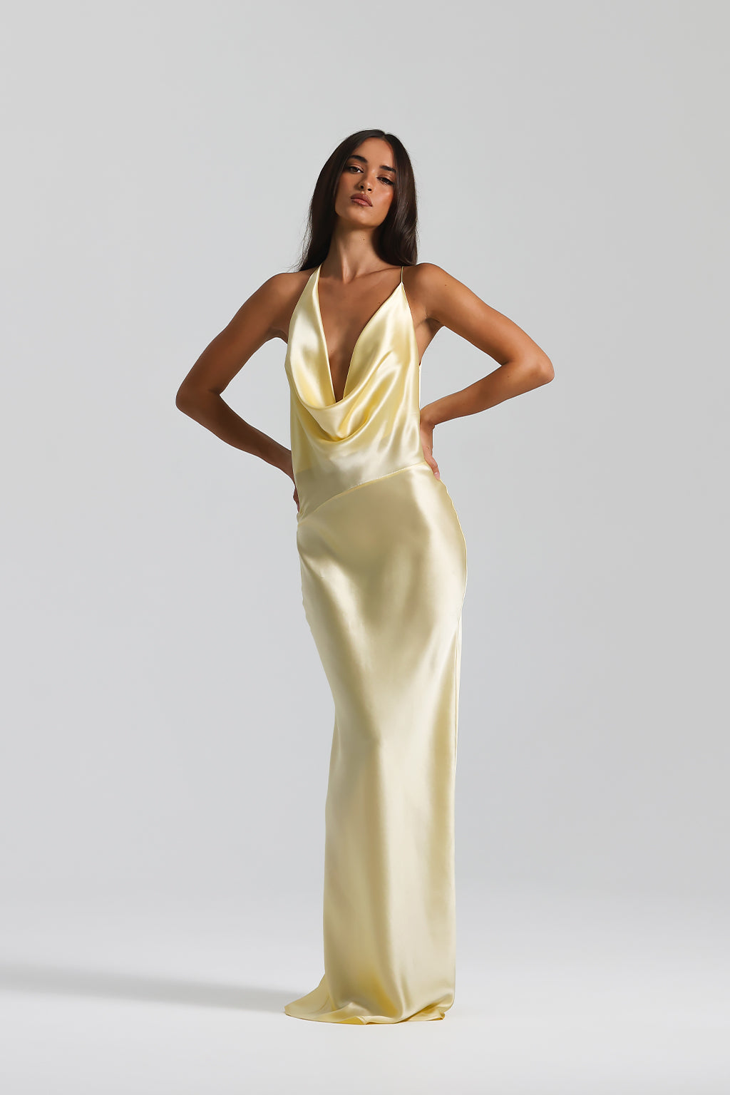 Woman wearing a gold satin gown against a plain background