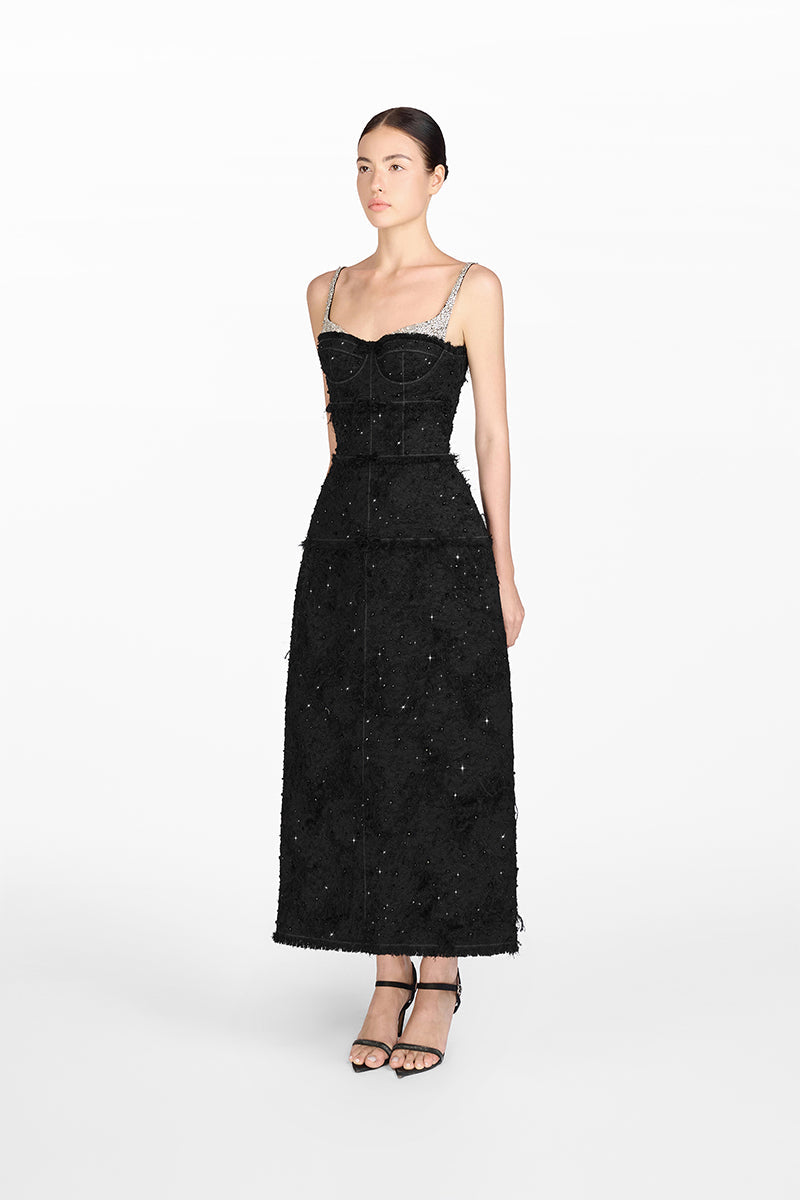 Woman wearing a black dress with silver embellishments on a white background