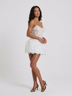 Woman wearing a white lace dress on a plain background