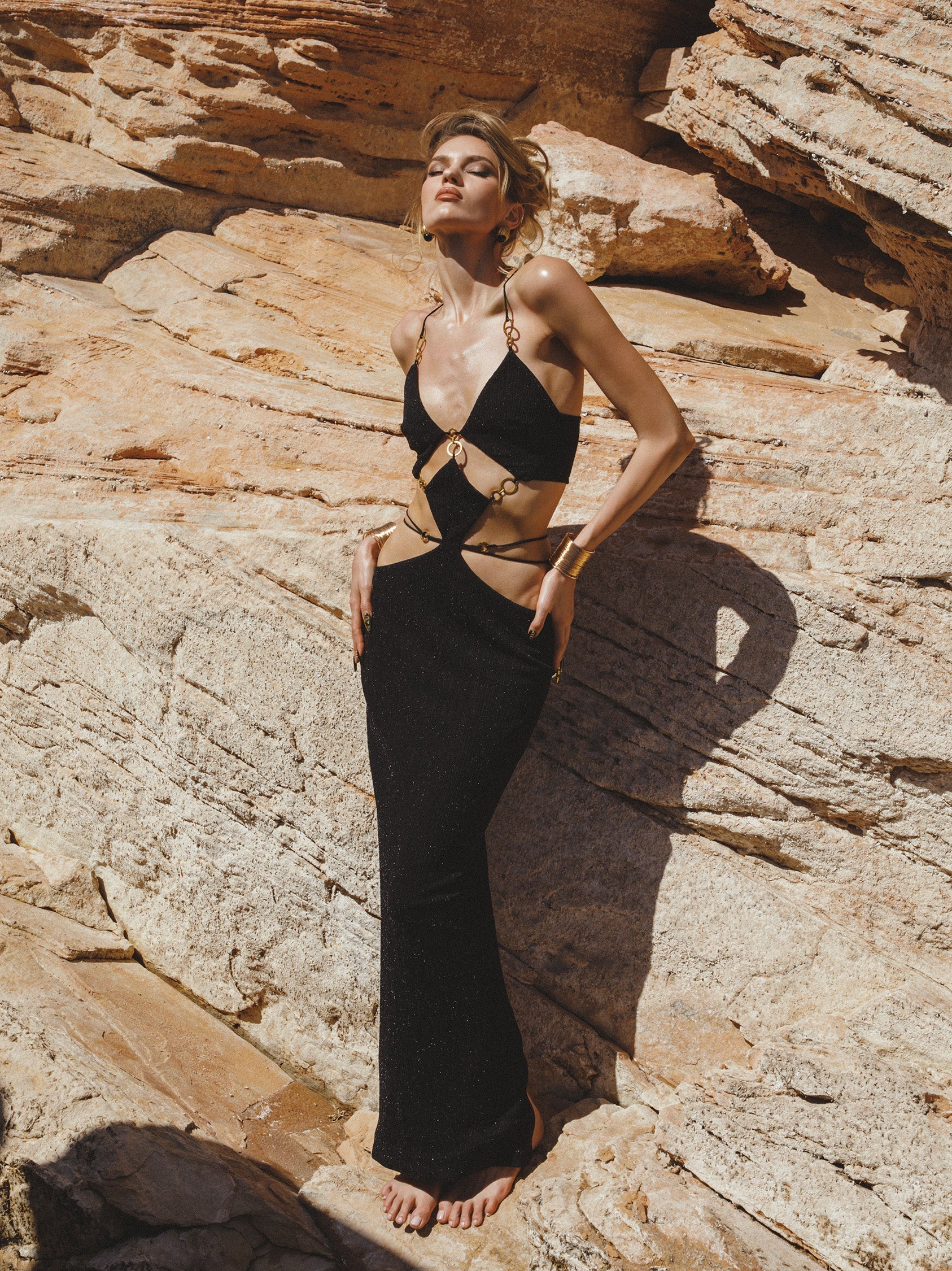 Woman in a black outfit standing on rocky terrain