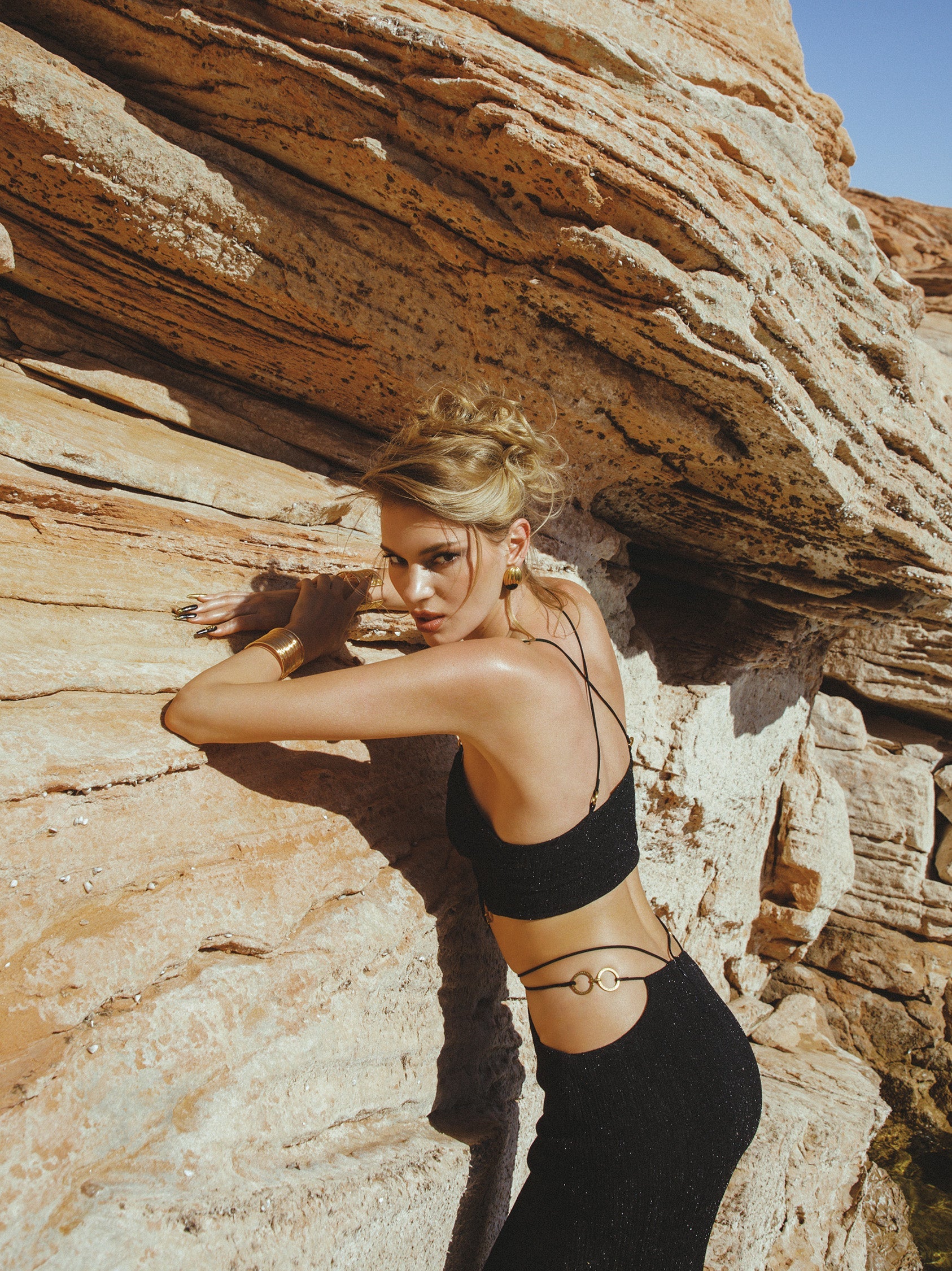 Woman in black athletic wear standing against a rock formation