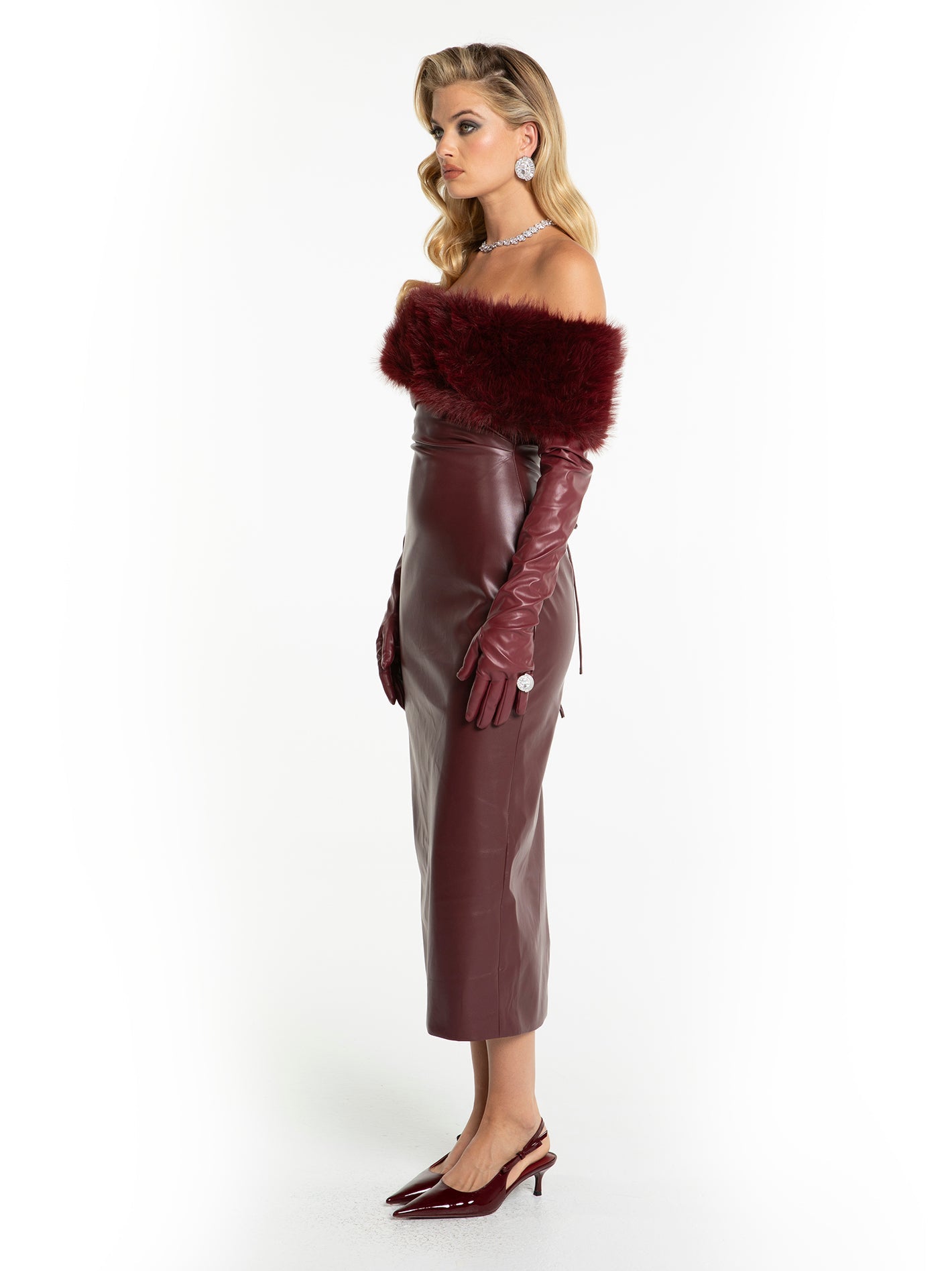 Woman wearing a burgundy leather dress with fur trim and gloves on a white background