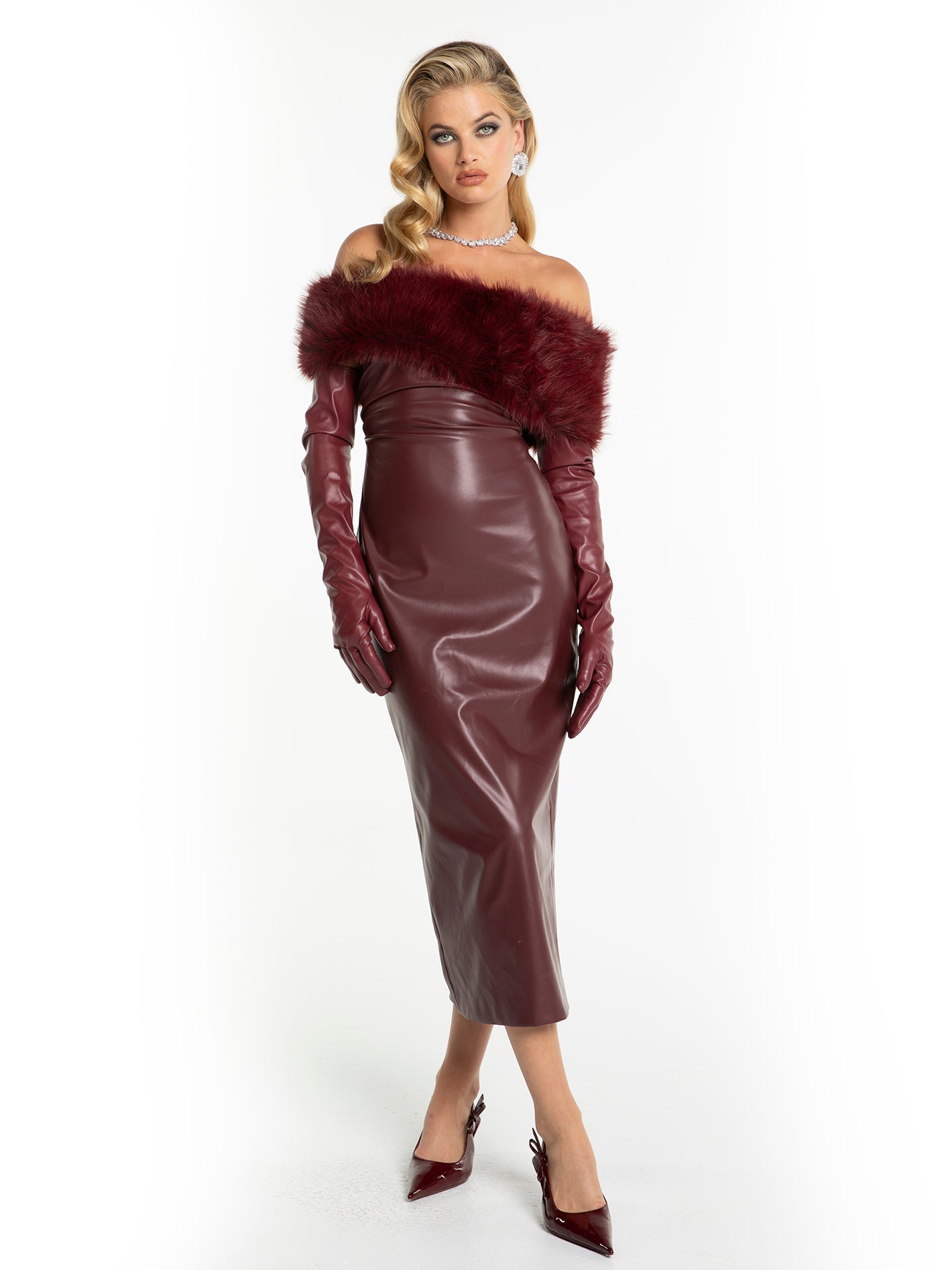 Woman wearing a burgundy leather dress with fur trim and matching gloves on a white background