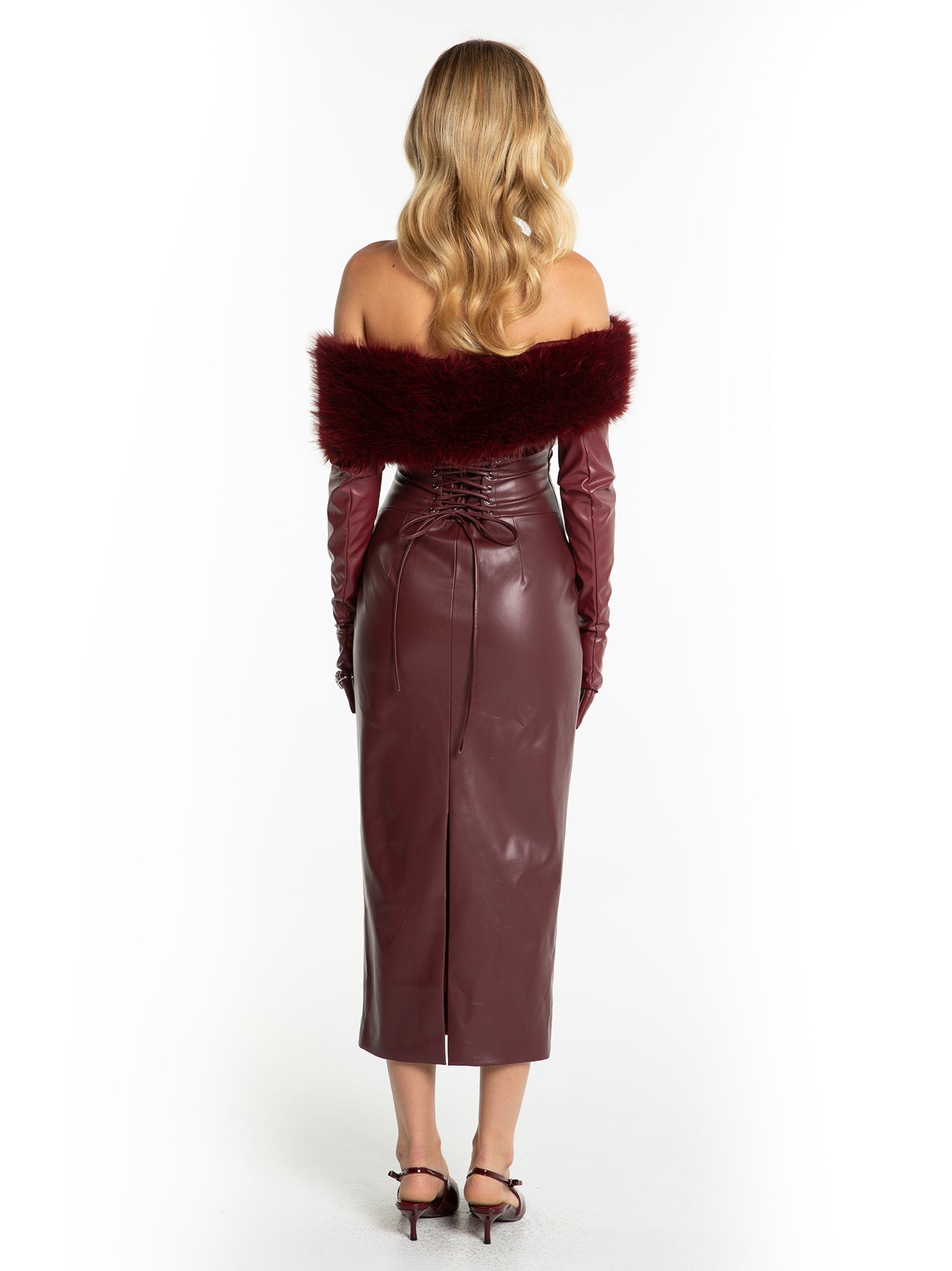 Woman wearing a burgundy leather dress with fur trim on a white background