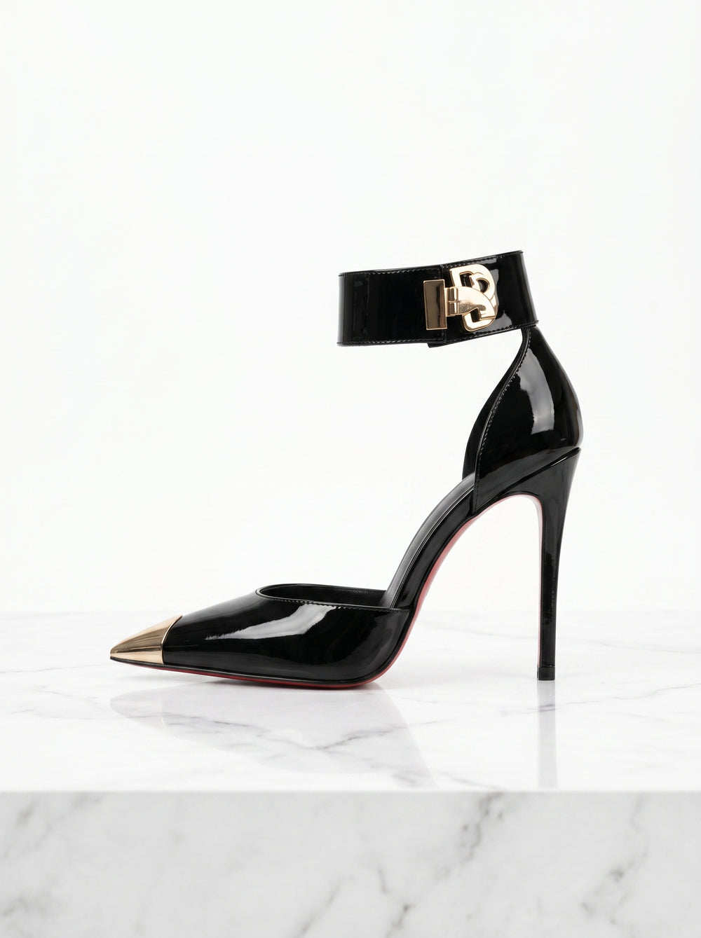 Black high-heeled shoe with gold accents on a white marble surface