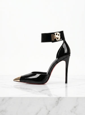 Black high-heeled shoe with gold accents on a white marble surface