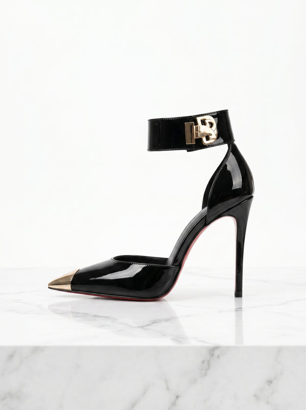 Black high-heeled shoe with gold accents on a white marble surface
