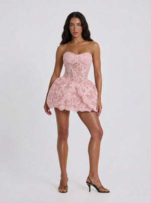 Woman wearing a pink lace strapless dress on a white background