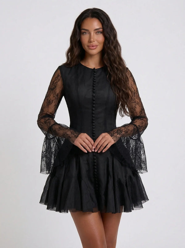 Black dress with sheer sleeves worn by a model on a white background