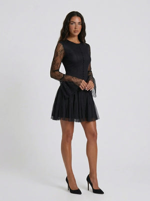 Woman wearing a black dress with sheer sleeves on a white background