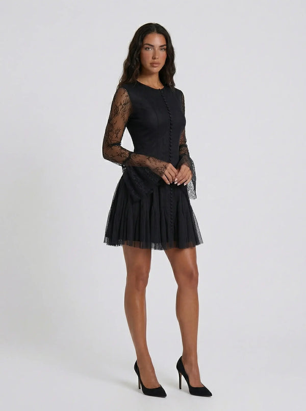 Woman wearing a black dress with sheer sleeves on a white background
