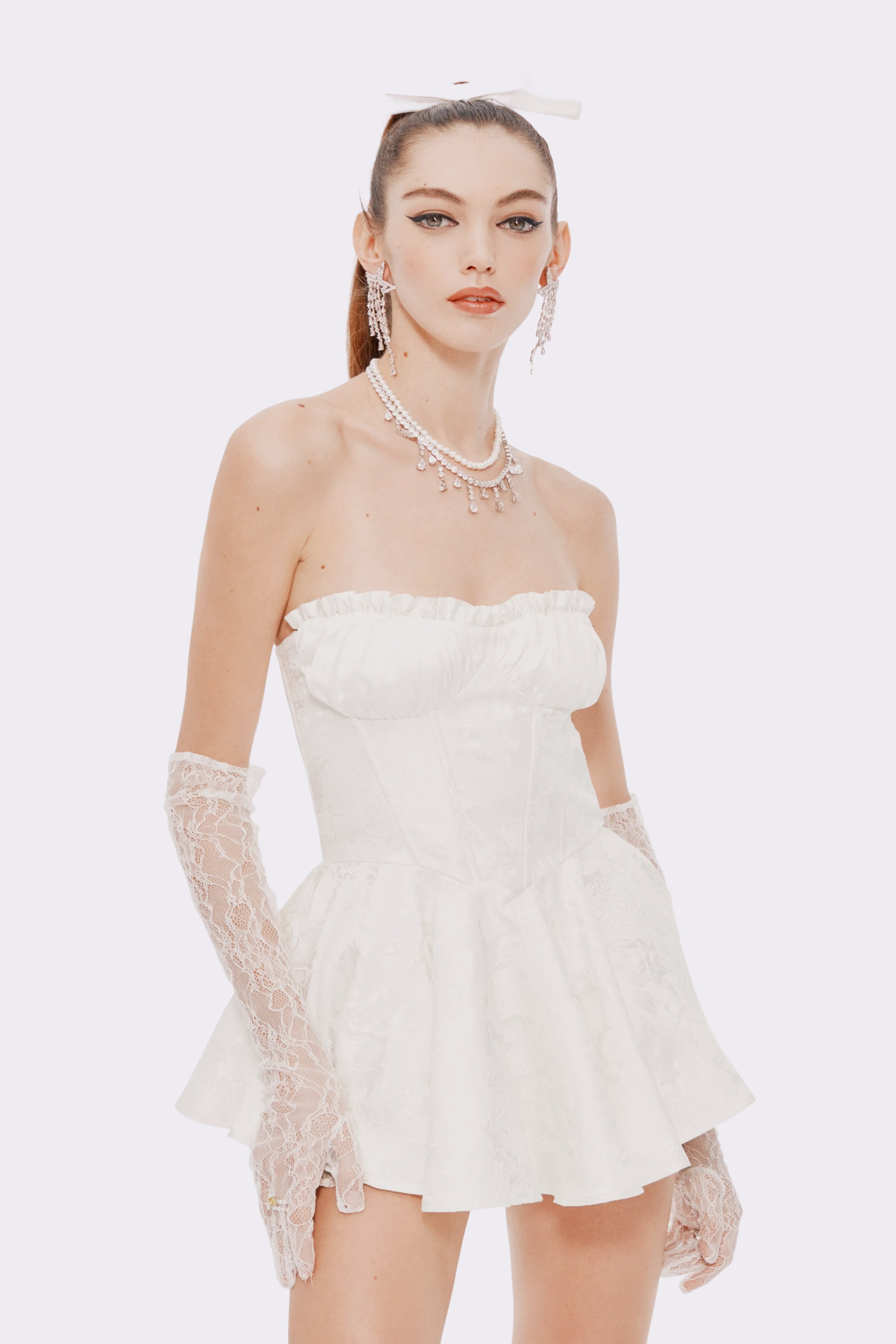 Woman wearing a white strapless dress with lace details on a white background
