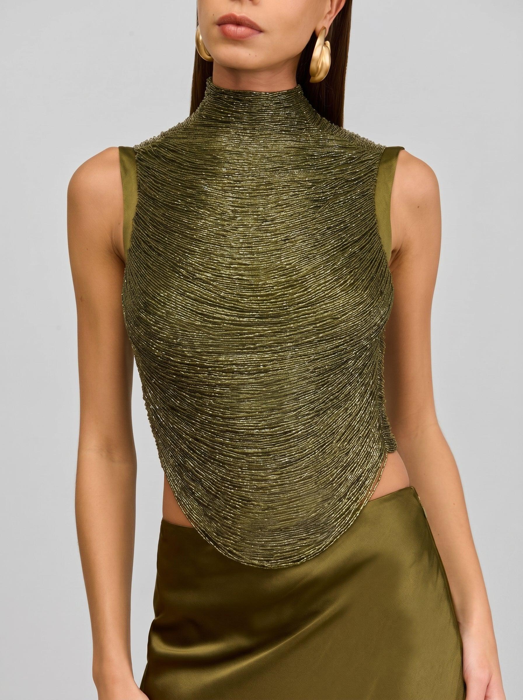 Woman wearing a green sleeveless top with a textured design on a gray background
