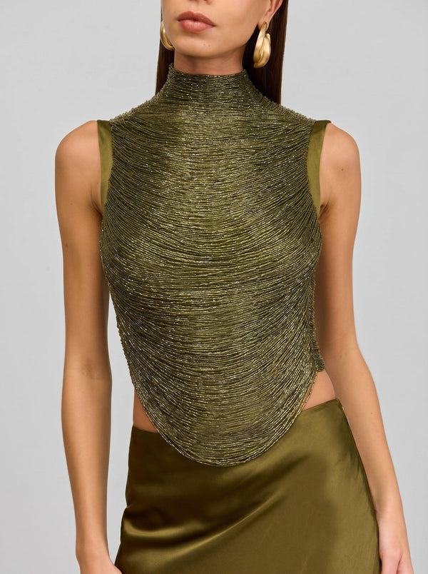 Woman wearing a green sleeveless top with a textured design on a gray background