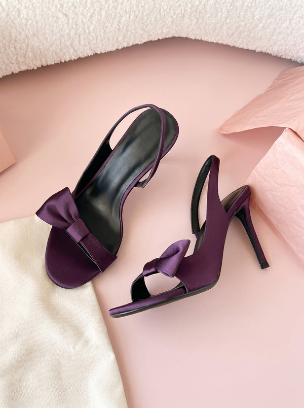 Bow Stiletto Slingback Sandal in plum purple — satin bow and slingback strap, flat lay on a linen cloth, VeroMarka