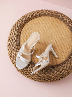 Knotted Stiletto Heeled Sandal in nude beige — satin knot and slim straps, flat lay on a rattan stool, VeroMarka
