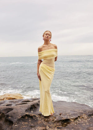Off-Shoulder Ruched Maxi Dress in buttermilk yellow, styled on a rocky seaside shore, VeroMarka