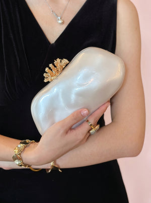 Pearl Coral Clasp Clutch in pearl white — pearlescent shell and gold coral clasp, held under the arm, VeroMarka