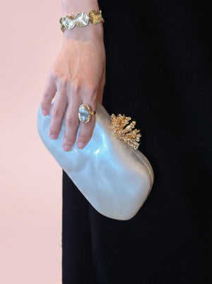 Pearl Coral Clasp Clutch in pearl white — pearlescent shell and gold coral clasp, held in one hand, VeroMarka
