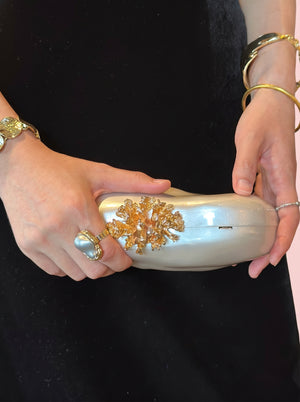 Pearl Coral Clasp Clutch in pearl white — pearlescent shell and gold coral clasp, held in both hands, VeroMarka