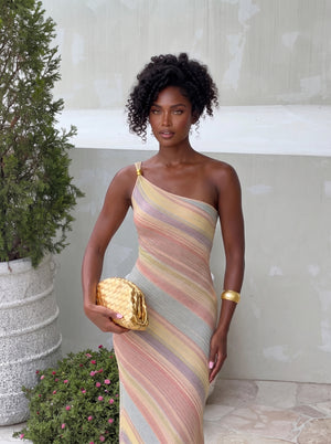 Rainbow Stripe One-Shoulder Maxi Dress in pastel multicolour, posed with a gold clutch, VeroMarka