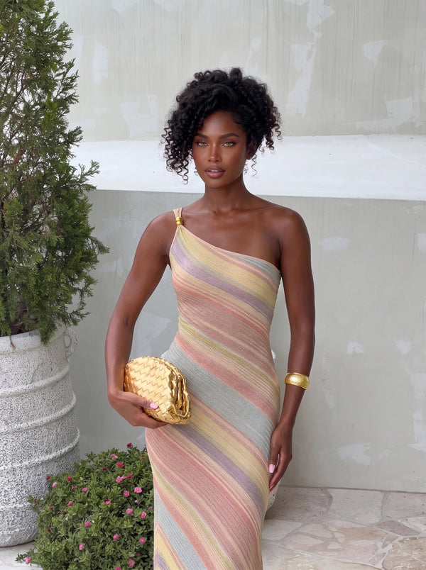 Rainbow Stripe One-Shoulder Maxi Dress in pastel multicolour, posed with a gold clutch, VeroMarka
