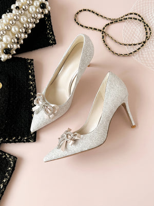 Sequin Bow Stiletto Heel in silver — crystal bow and glitter finish, flat lay with pearl and tweed accessories, VeroMarka