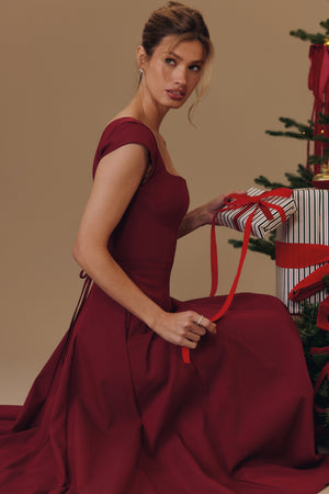 Square Neck A-Line Midi Dress in burgundy, seated beside a Christmas tree with a gift, VeroMarka