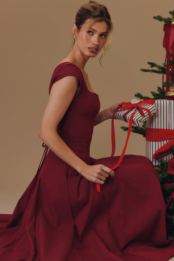 Square Neck A-Line Midi Dress in burgundy, seated beside a Christmas tree with a gift, VeroMarka